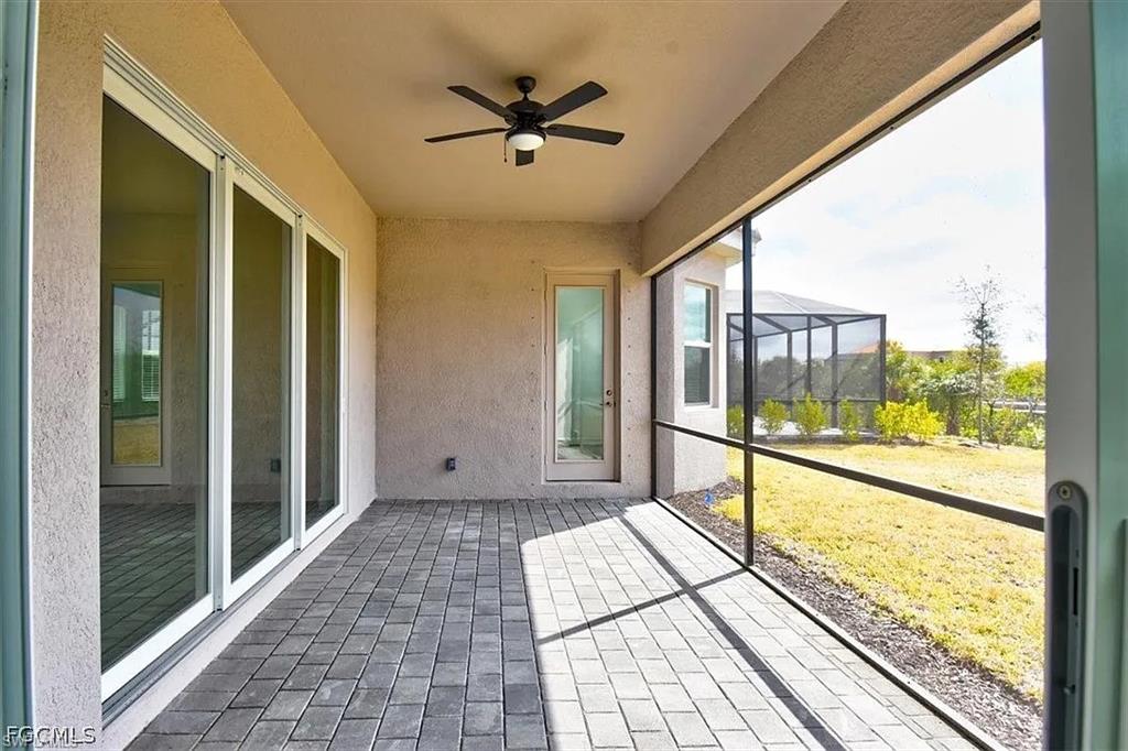 Screened lanai featuring paver flooring, a ceiling fan, and sliding glass doors