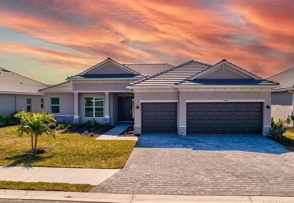 Contemporary residence featuring a two-car garage, paver driveway, and a tiled roof