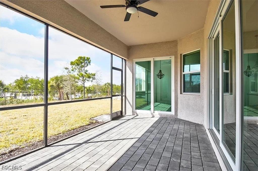 Screened patio featuring gray paver flooring and a ceiling fan