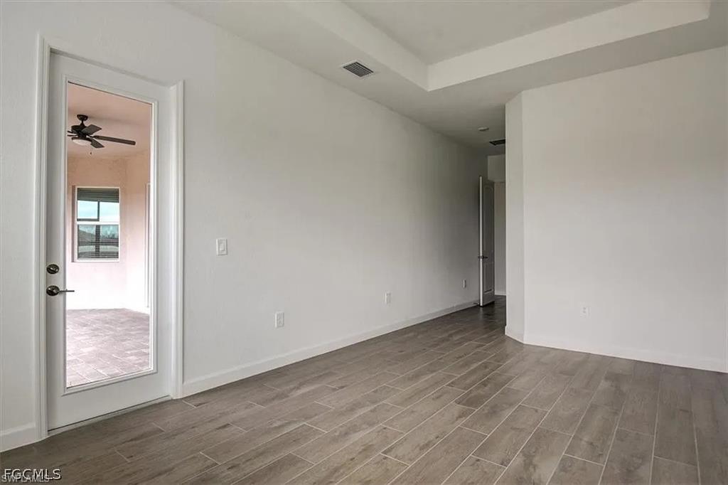Spacious interior room featuring wood-finish tile flooring, a tray ceiling, and fresh white walls