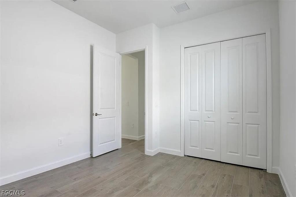 Room featuring light wood-finish flooring, white walls, and a white bi-fold closet door