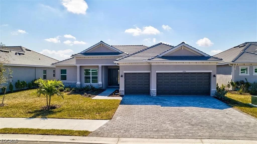 Modern stucco exterior with stone accents, a paver driveway, and a two-car garage