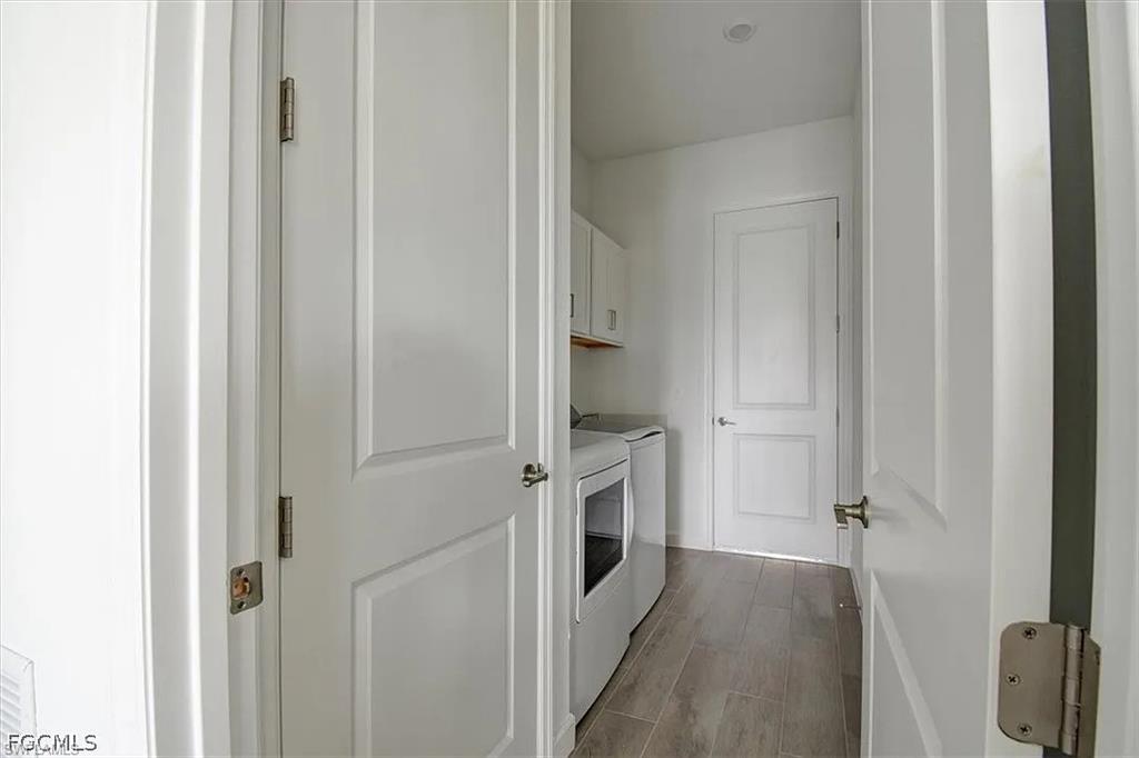 Dedicated laundry area featuring wood-finish flooring, white cabinetry, and recessed lighting
