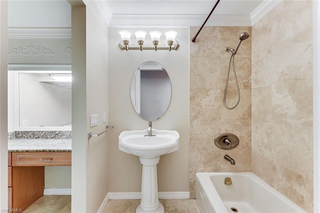 Pedestal sink with an oval mirror and brushed nickel lighting fixture