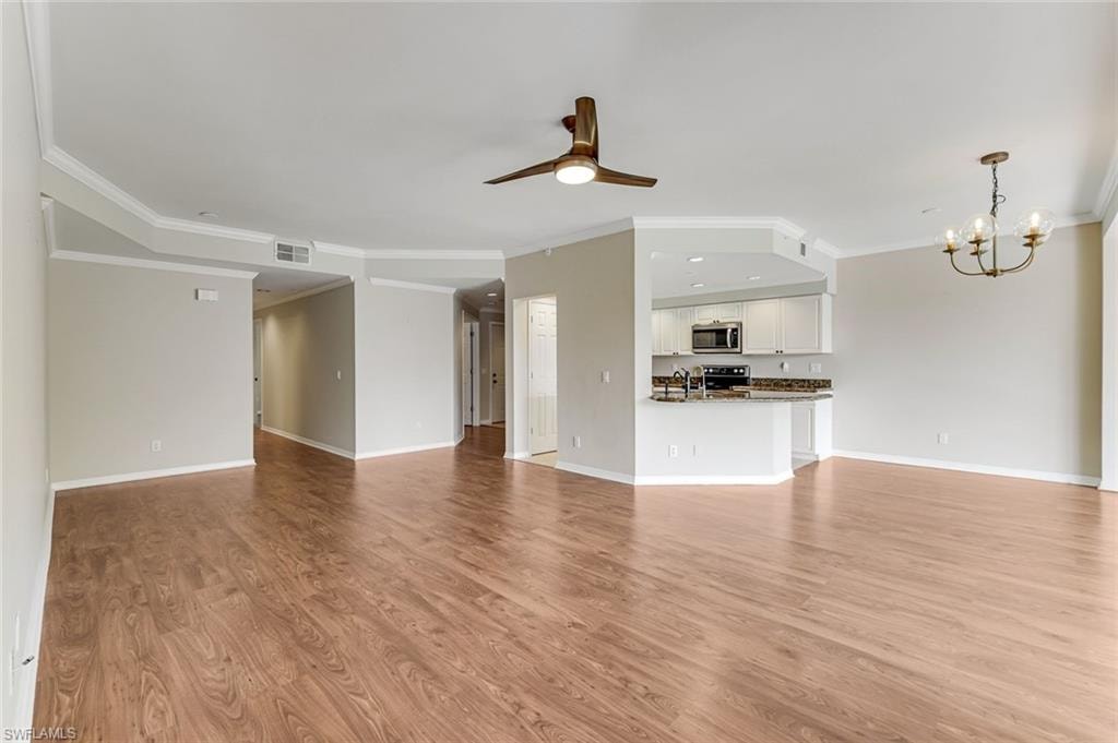 Open-concept living area featuring wood-finish flooring, crown molding, and a ceiling fan