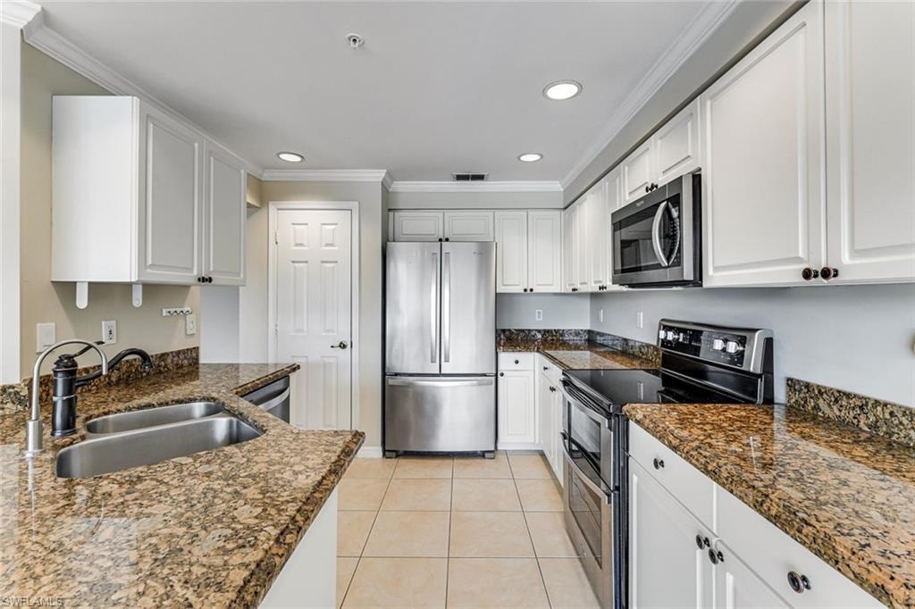 Kitchen featuring granite countertops, white cabinetry, stainless steel appliances, a double basin sink, and recessed lighting