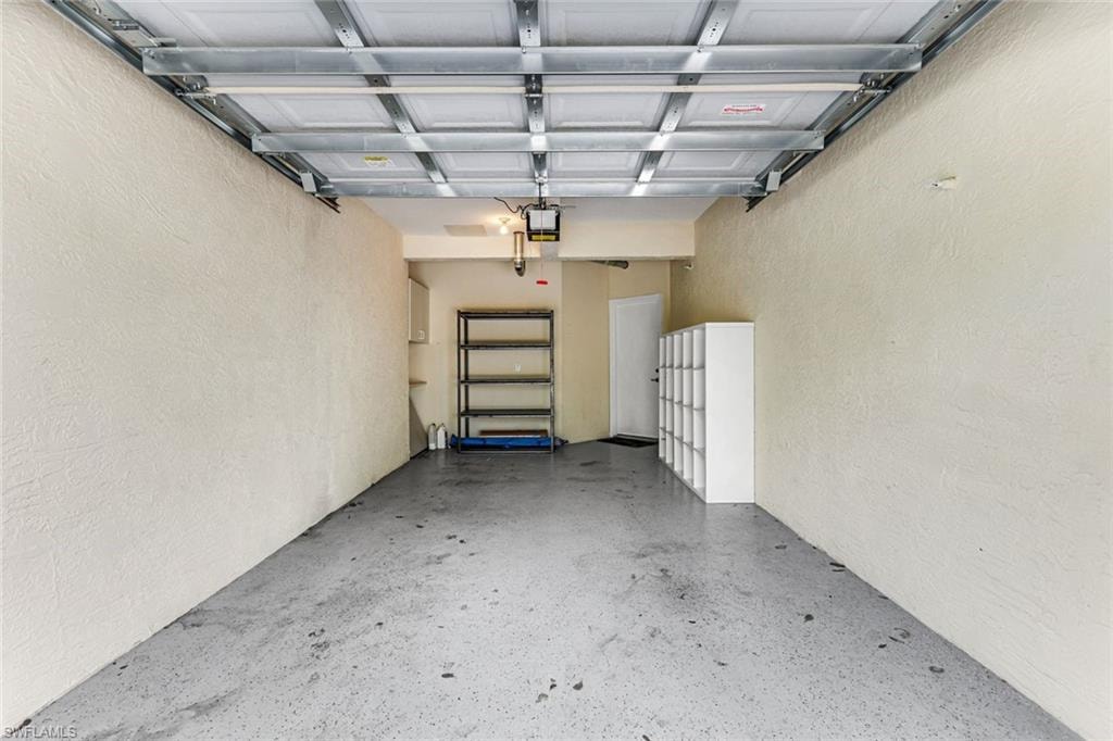 Spacious garage featuring textured walls, a gray epoxy floor, and a white overhead door