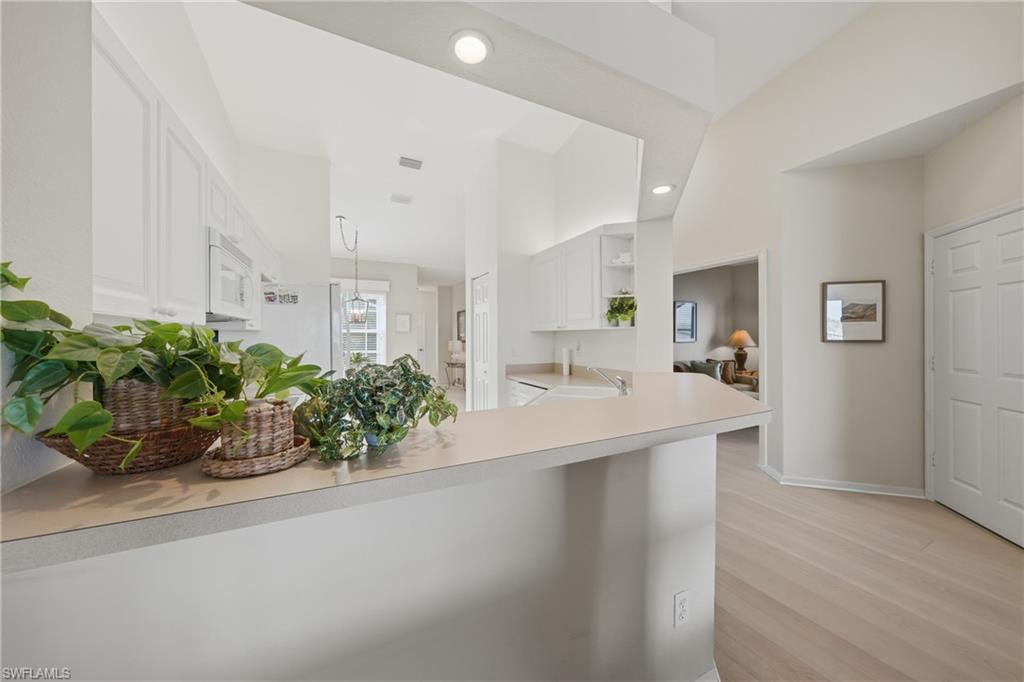 Kitchen with white cabinetry, a built-in microwave, and a breakfast bar featuring a light-toned countertop