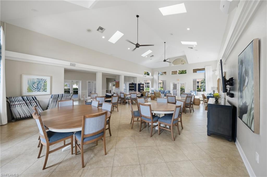 Spacious common area featuring vaulted ceilings, multiple skylights, recessed lighting, ceiling fans, and neutral tile flooring