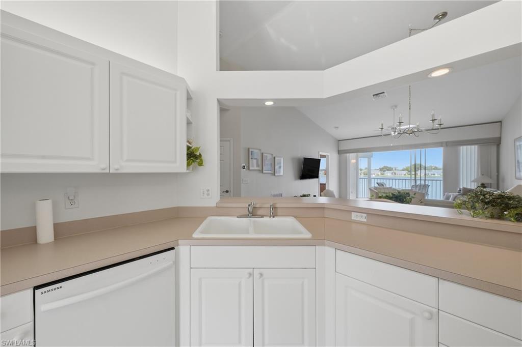 Kitchen featuring white cabinetry with raised panel doors, a double basin sink, and integrated dishwasher