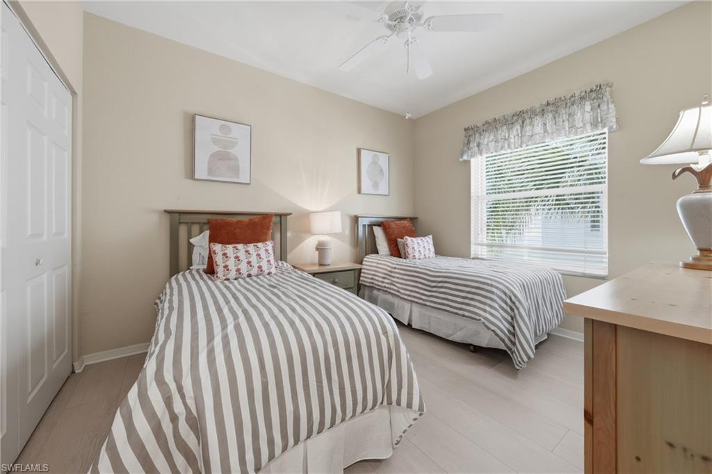Light-toned flooring complemented by a window with blinds, a ceiling fan, and a built-in closet with bi-fold doors
