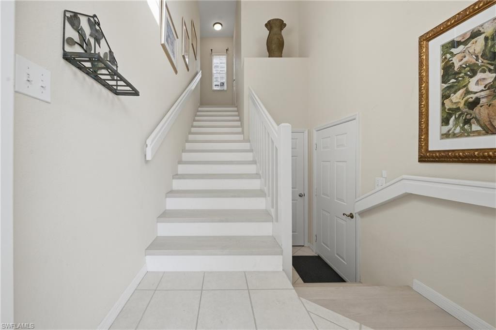 Staircase featuring white risers and light-toned treads, white handrails, and neutral wall paint