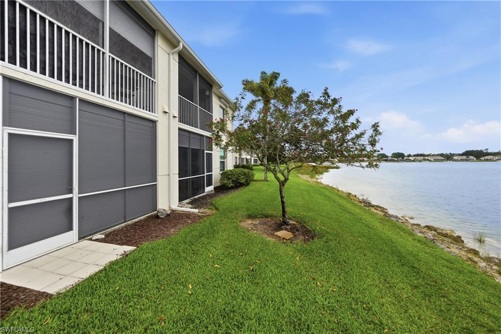 Lakeside property featuring screened patios and balconies, a mature tree, and a grassy bank leading to the water