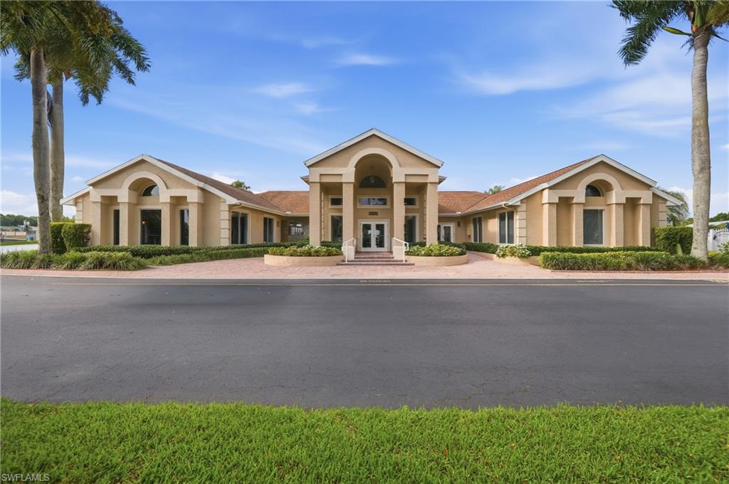 Stucco exterior with a terracotta tile roof, featuring a grand entrance with columns and archways