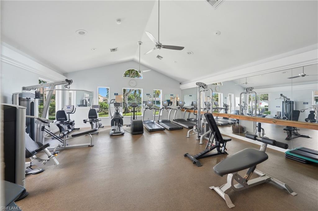 Fitness center featuring a high vaulted ceiling with ceiling fans, multiple windows, large wall-mounted mirrors, and durable flooring