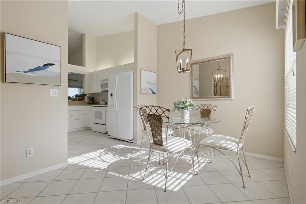 Dining area with ceramic tile flooring, a contemporary chandelier, and a mirrored wall accent