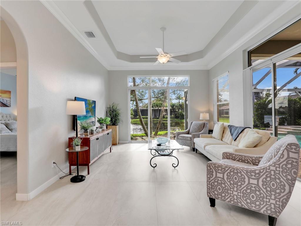 Living room featuring a ceiling fan, arched walkways, and a tray ceiling