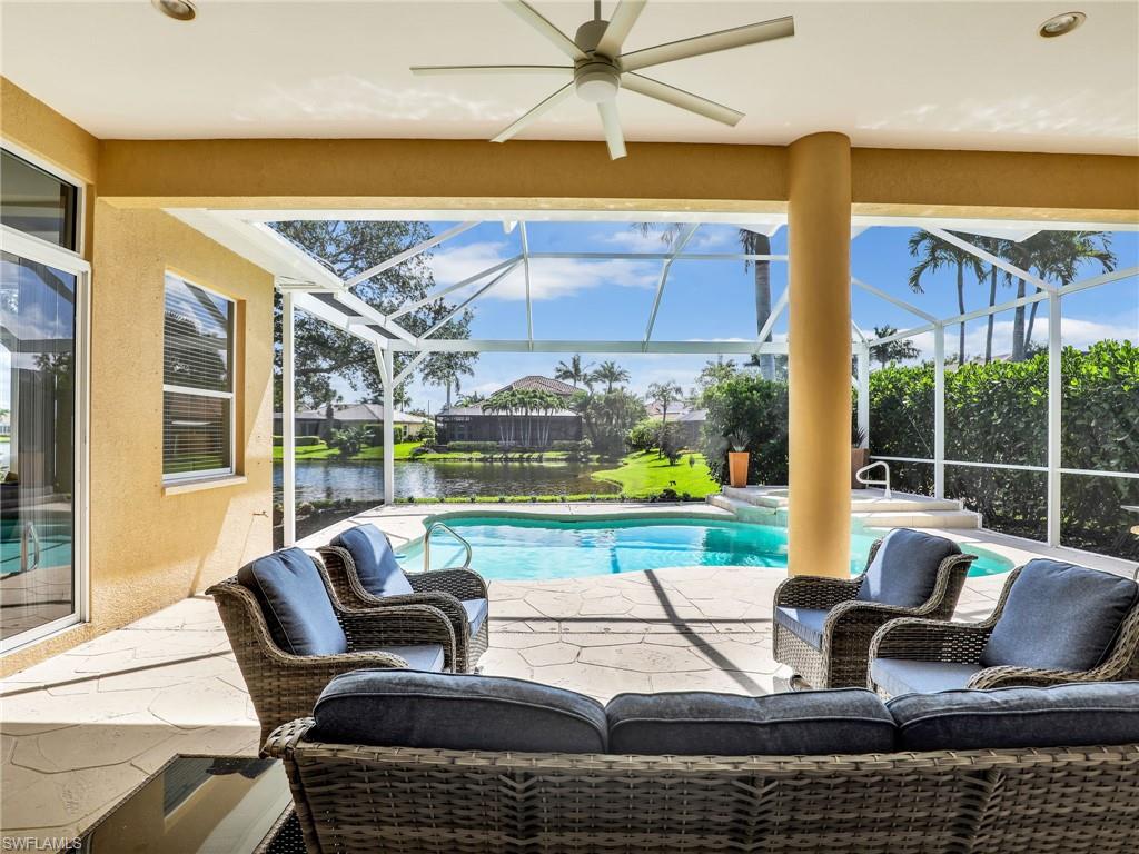View of pool with a patio area, glass enclosure, ceiling fan, and a pool with connected hot tub