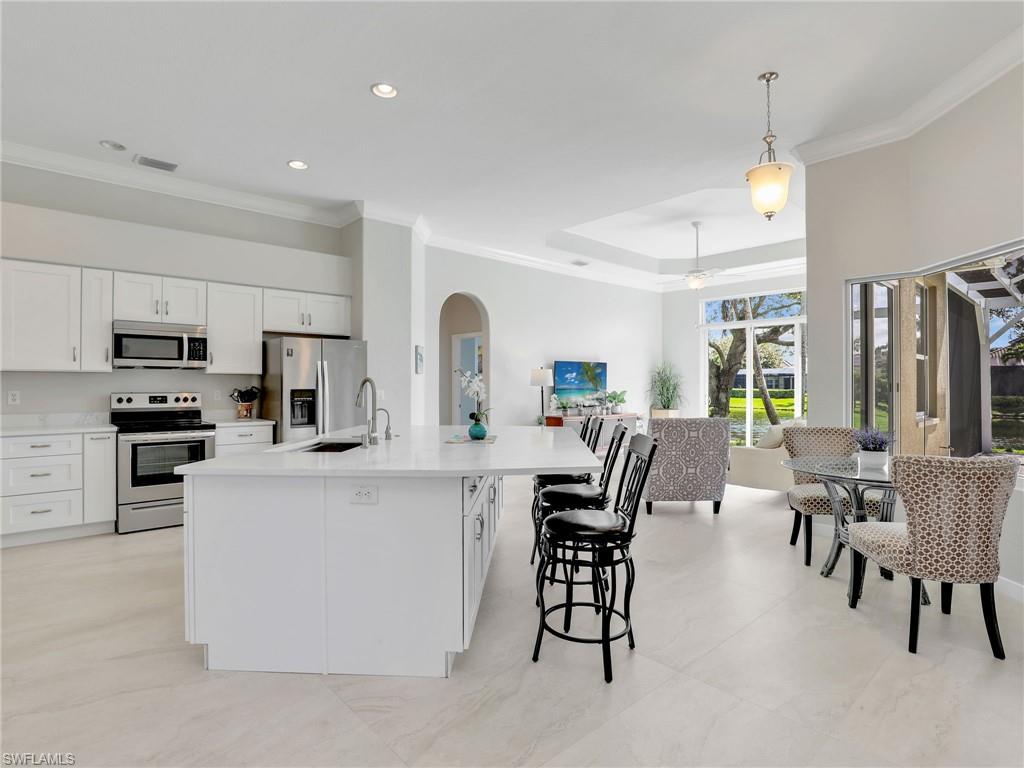 Kitchen featuring appliances with stainless steel finishes, open floor plan, white cabinetry, light countertops, and arched walkways