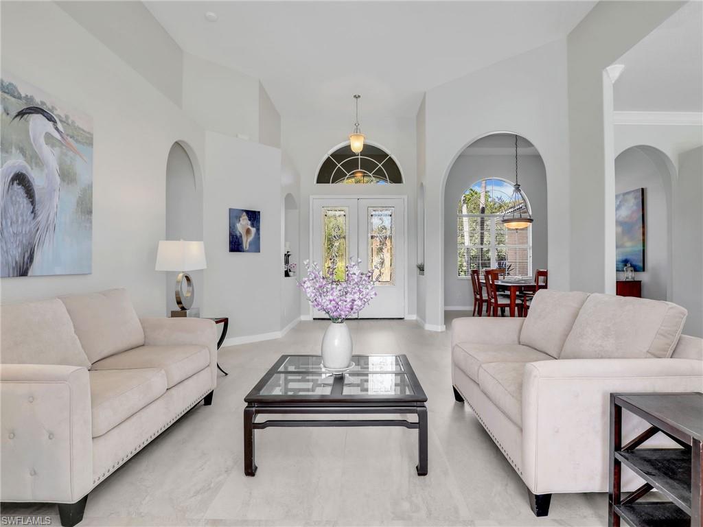 Living area with arched walkways, high vaulted ceiling, and french doors