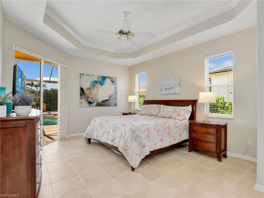 Bedroom with a tray ceiling, access to exterior, ornamental molding, and multiple windows