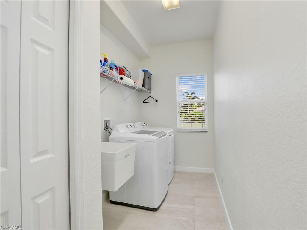 Washroom featuring washing machine and clothes dryer and baseboards