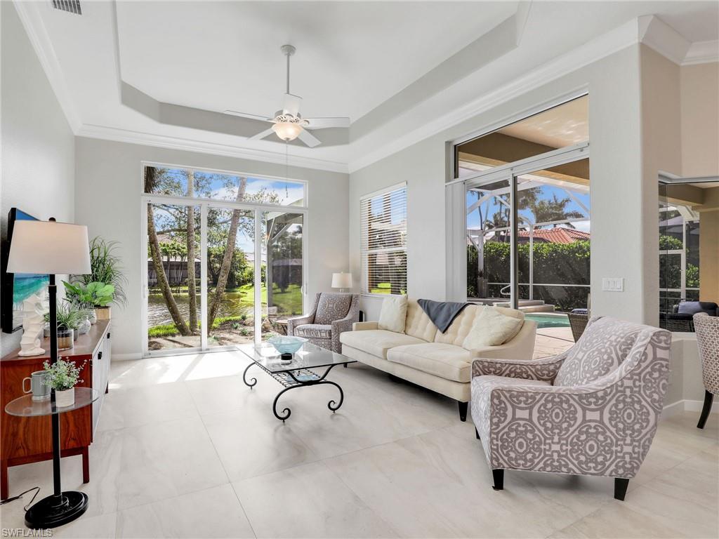 Living room with ceiling fan, crown molding, and a raised ceiling