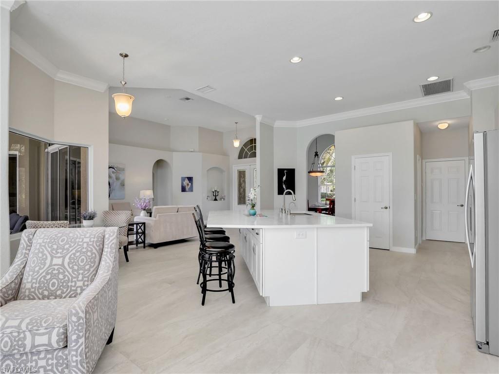Kitchen with open floor plan, arched walkways, freestanding refrigerator, ornamental molding, and light countertops