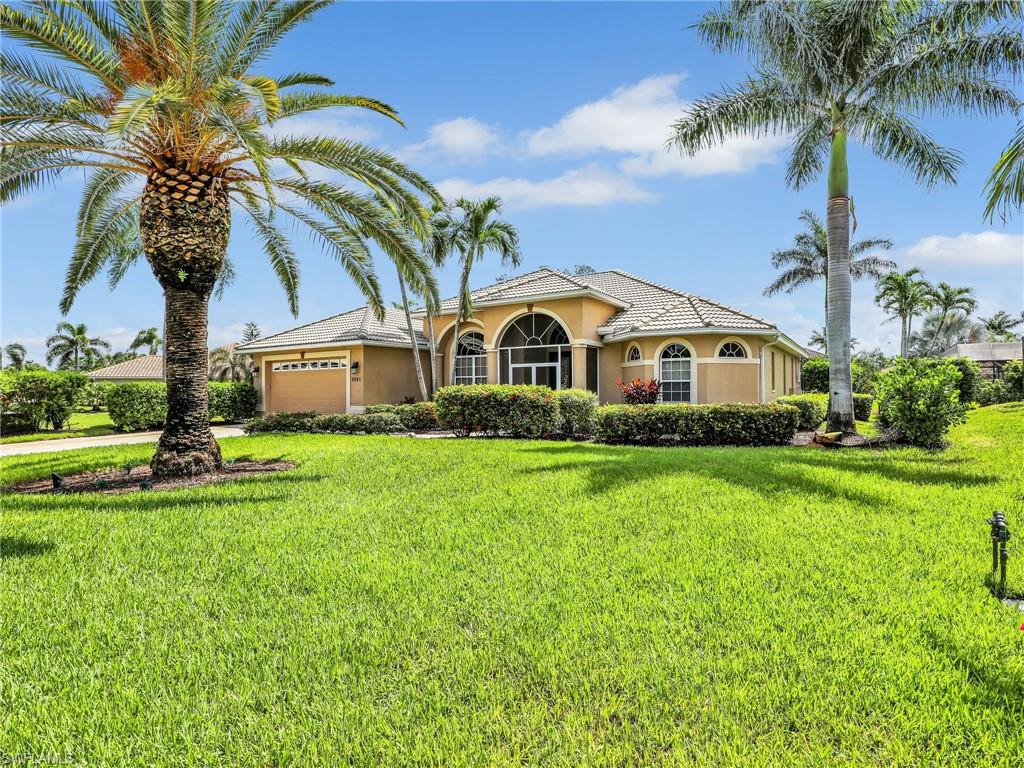 Mediterranean / spanish home featuring stucco siding, a garage, a front lawn, and driveway
