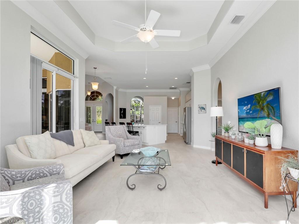 Living area with arched walkways, a tray ceiling, a ceiling fan, and recessed lighting