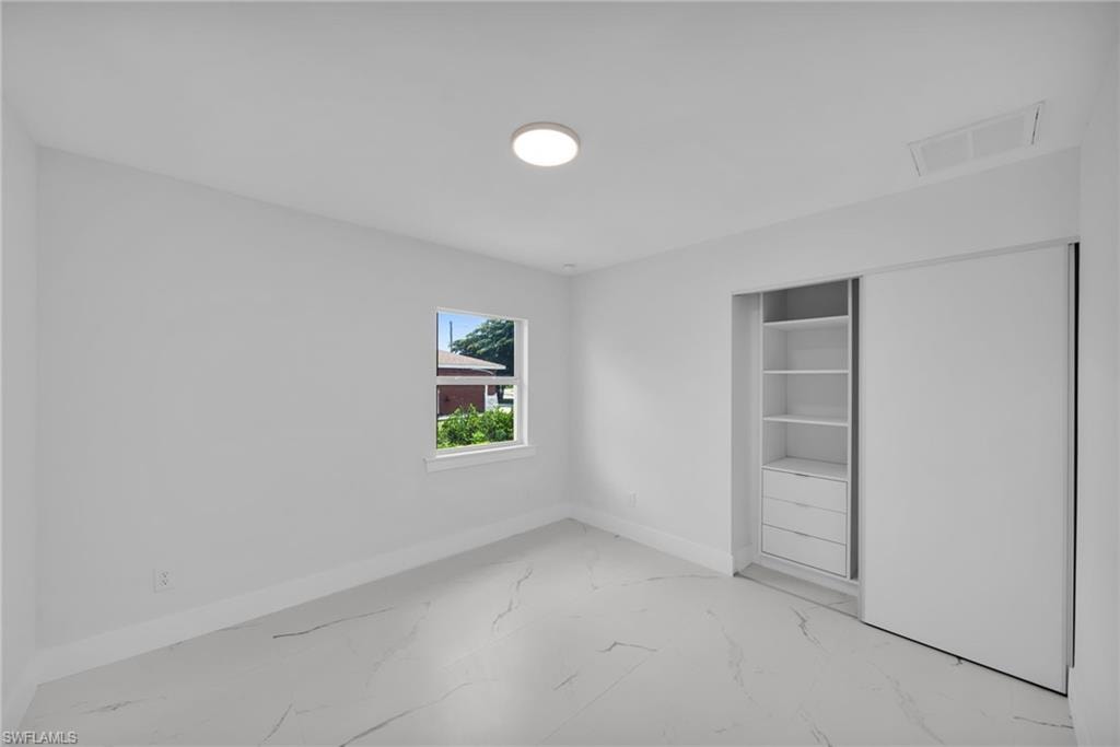 Bedroom featuring a single window, a flush-mount ceiling light, light-toned walls, and a built-in closet system with sliding doors and integrated shelving