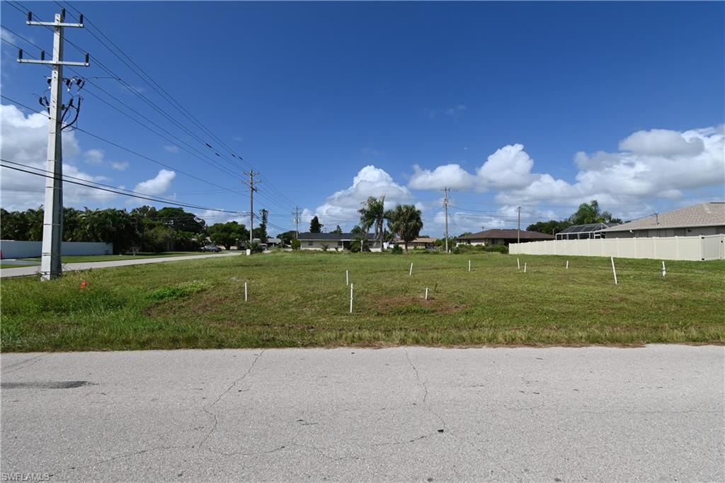 Expansive cleared lot featuring level terrain, a partial rear privacy fence, and paved road frontage