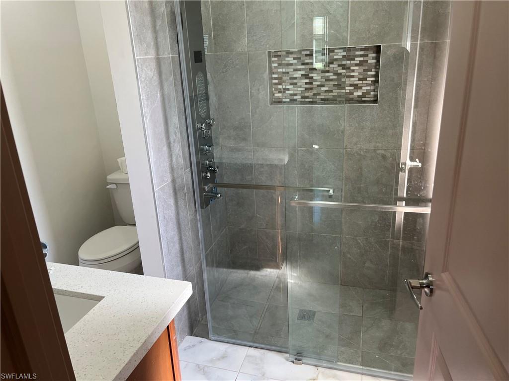 Bathroom featuring an enclosed shower, vanity, and toilet