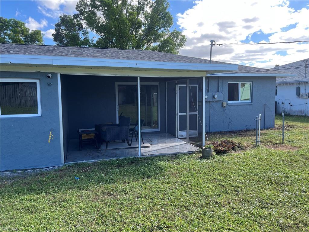 Rear view of house featuring a sunroom, a patio area, and a yard