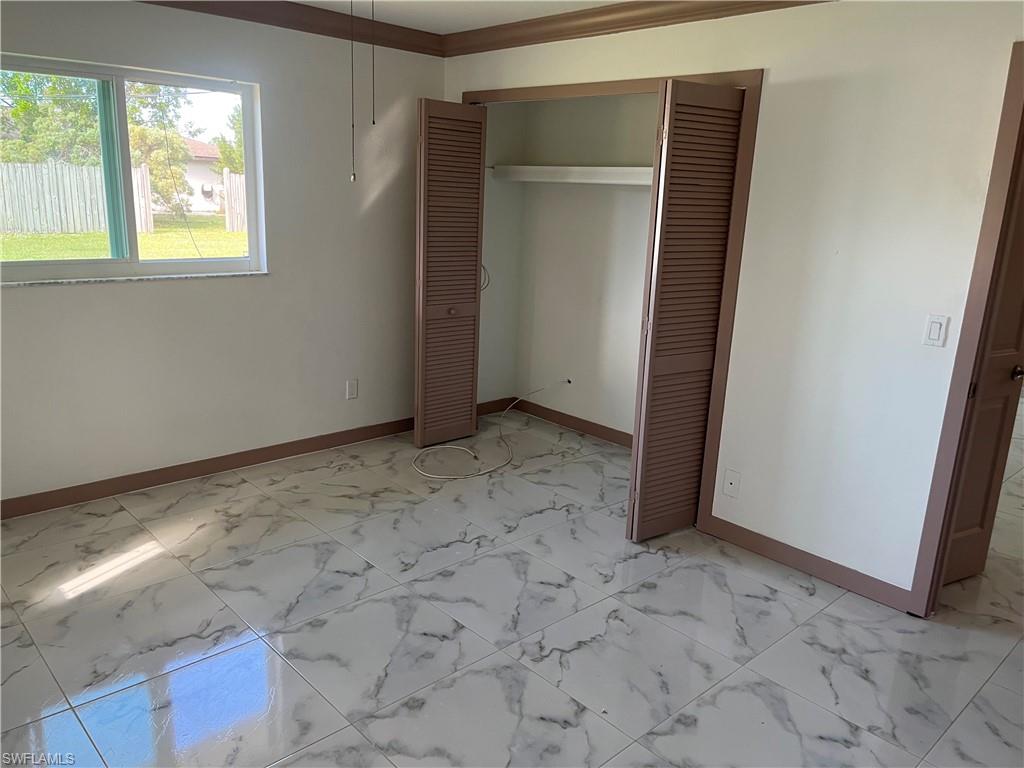 Unfurnished bedroom with a closet and crown molding