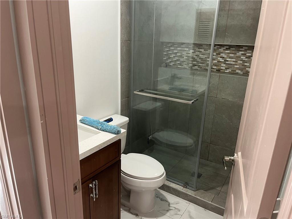 Bathroom featuring vanity, a shower with shower door, and toilet
