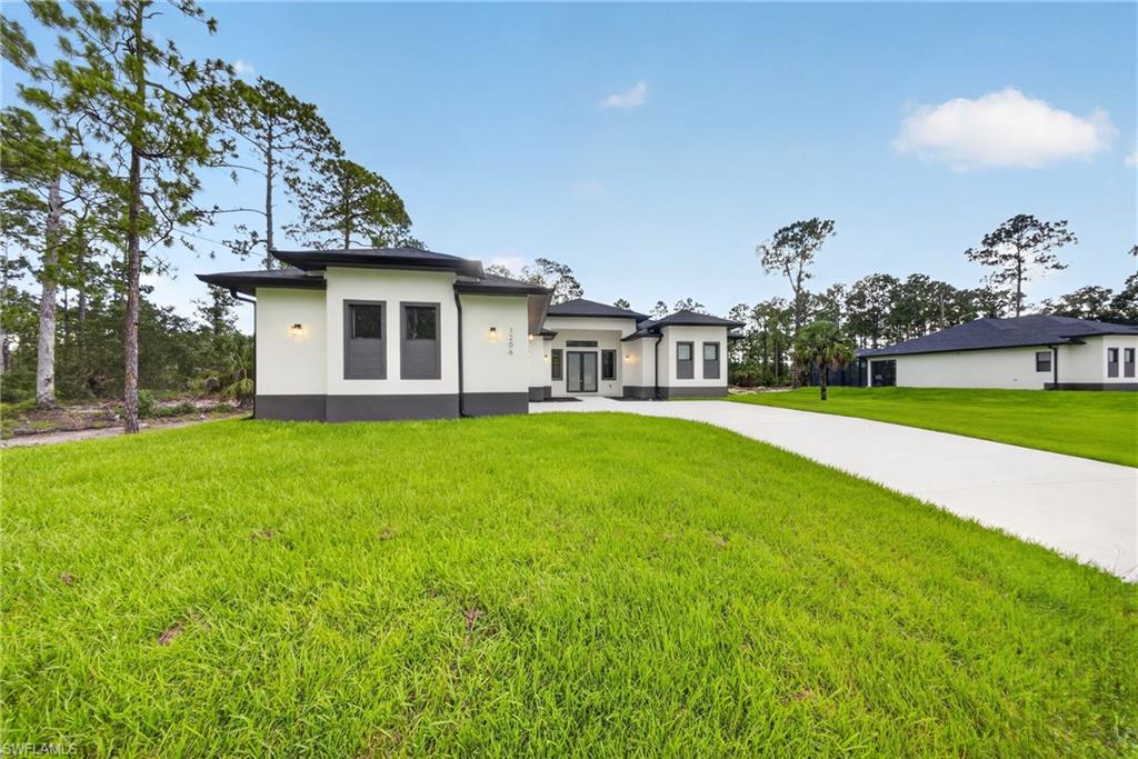 Modern architecture with a white and charcoal exterior, featuring a long concrete driveway, integrated outdoor lighting, and a manicured green lawn