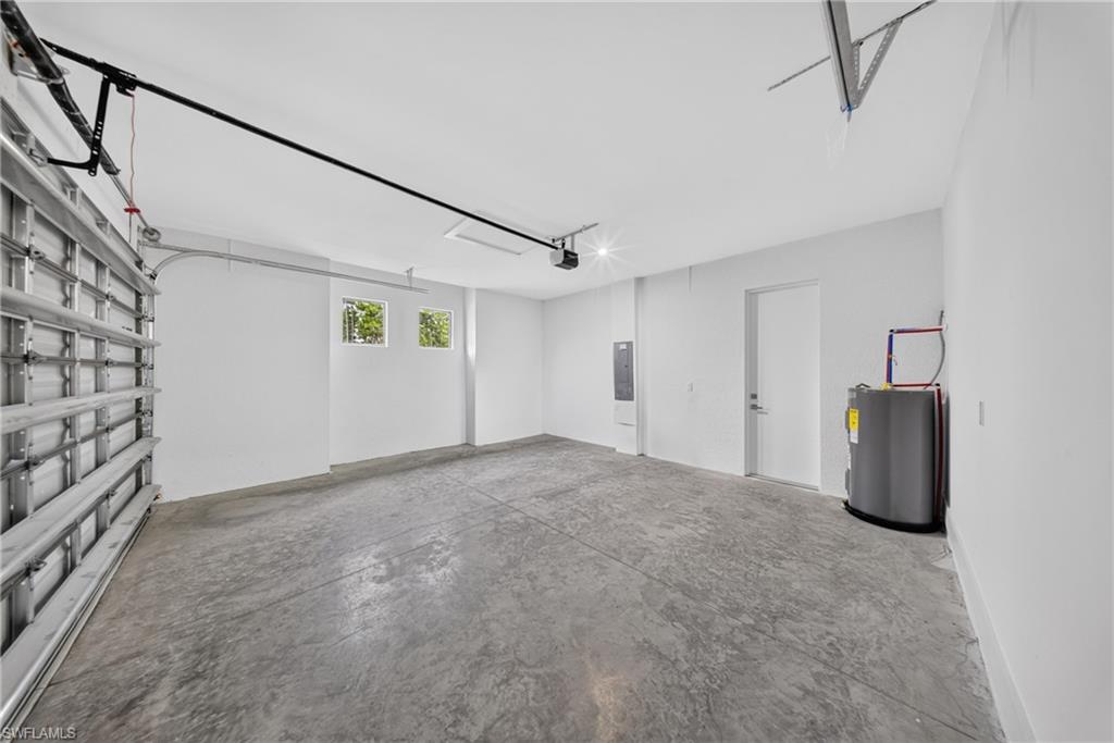 Spacious garage featuring a concrete floor, bright white walls, and a visible water heater