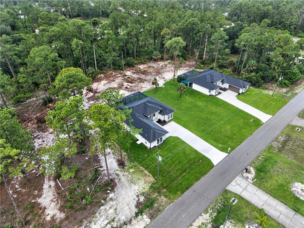 Aerial perspective showcasing two single-story homes, each with a dark shingle roof and a screened enclosure
