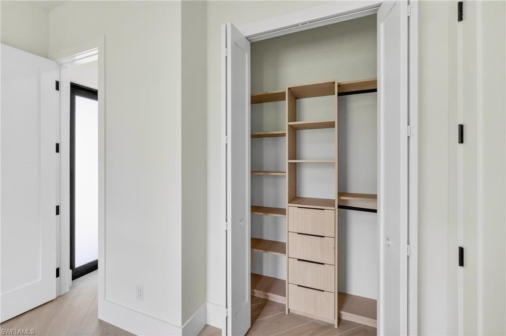 Custom closet system with light wood-finish shelving and integrated drawers, complemented by a hanging rod