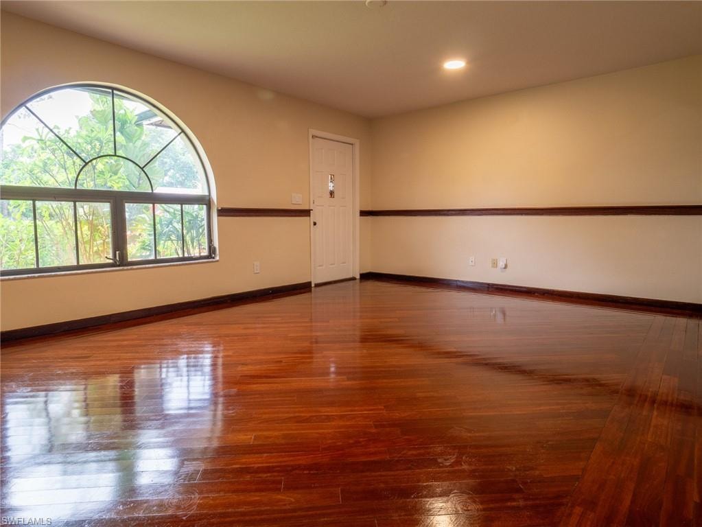 Room featuring wood flooring, a half-round transom window, recessed lighting, and a white paneled door