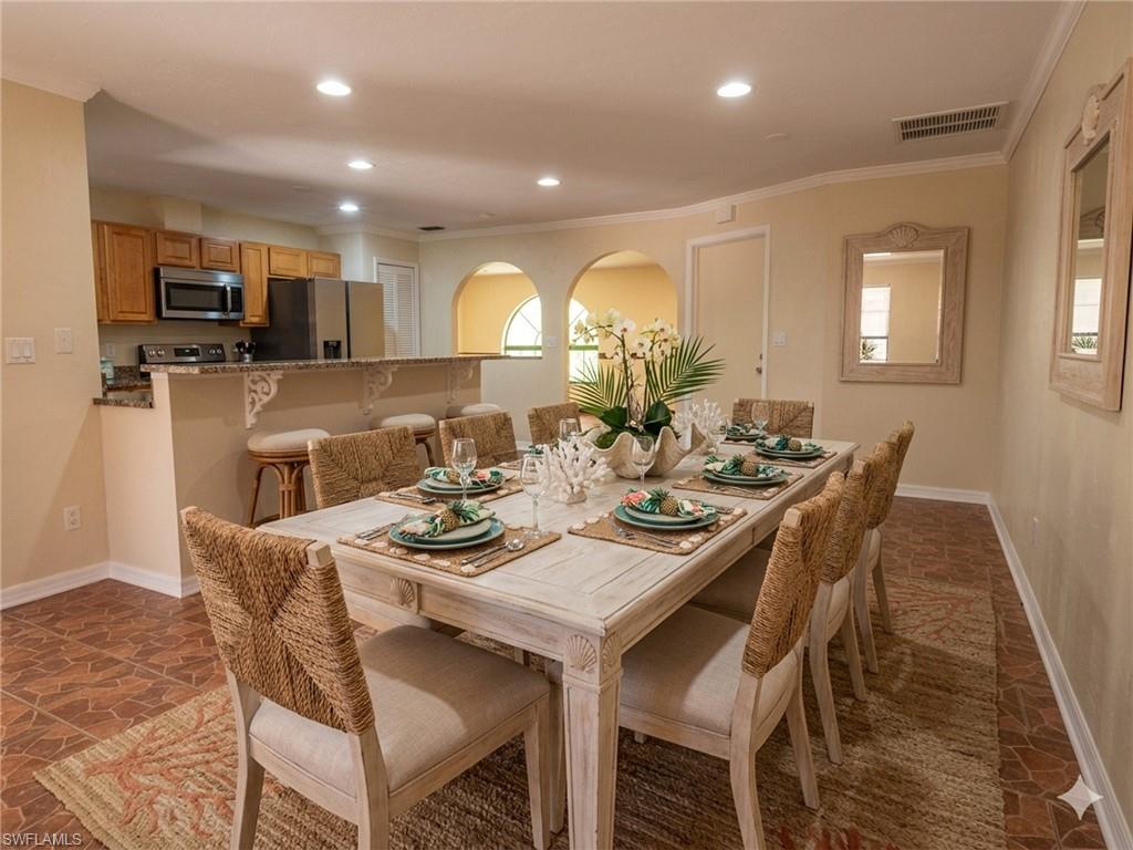 Dining area featuring a wood-finish dining table and tile flooring, with an arched opening to an additional room