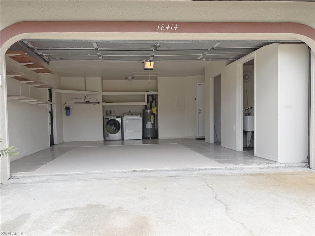 Spacious garage featuring a finished floor, built-in shelving, a dedicated laundry area with washer and dryer hookups, and a water heater