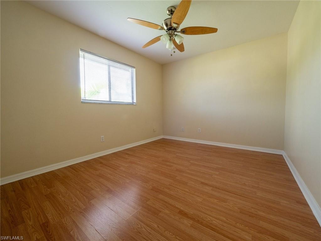Room featuring wood-finish flooring, a window with horizontal blinds, and a ceiling fan with integrated lighting