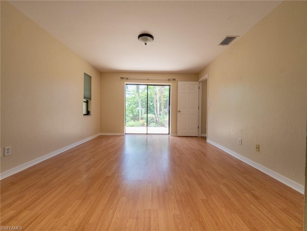 Expansive room featuring wood-finish flooring, neutral-toned walls, and a recessed window