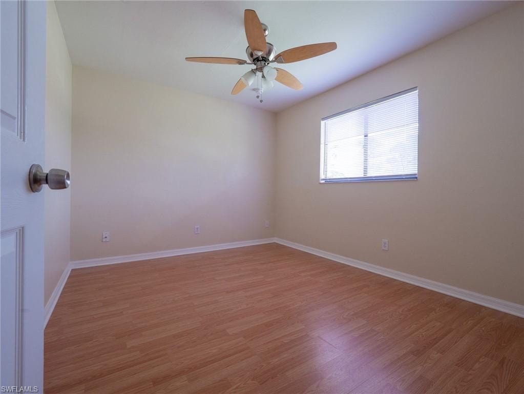 Well-lit room featuring wood-finish flooring, a ceiling fan with light fixture, and a window with horizontal blinds