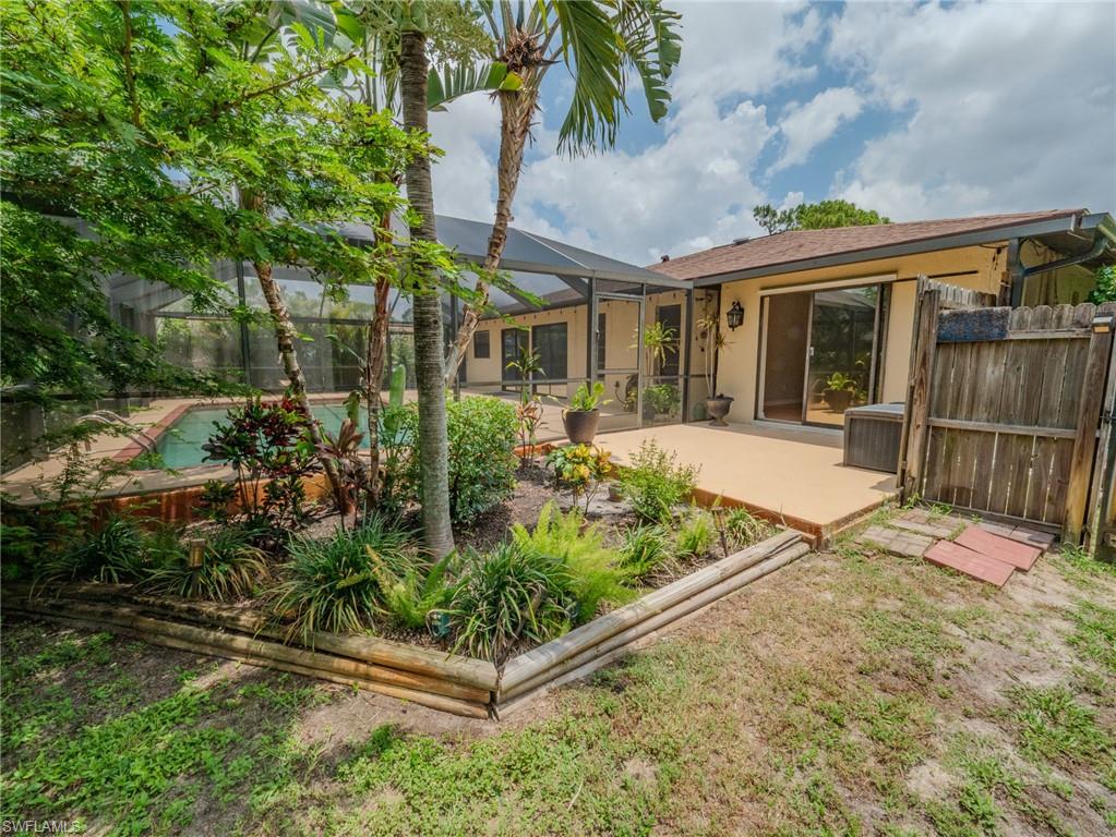 Screened-in pool area featuring a patio deck and mature landscaping