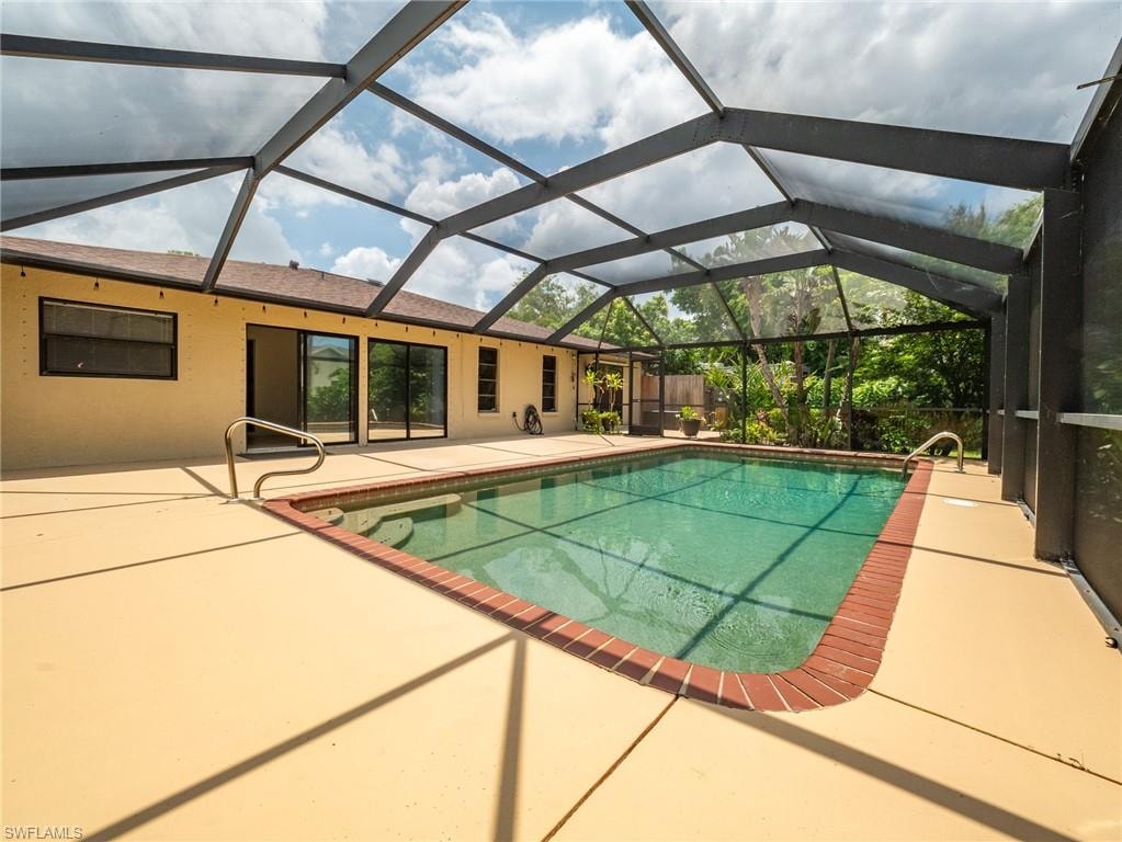 Screen-enclosed swimming pool with a brick coping, surrounded by a spacious deck