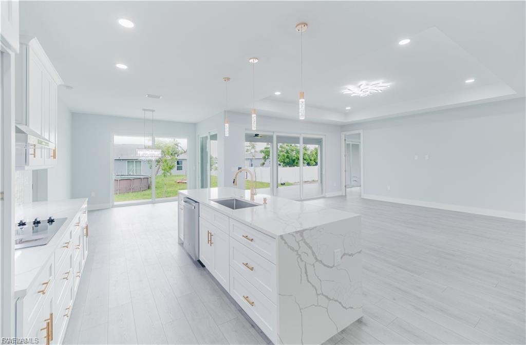 Spacious kitchen featuring an expansive island with a waterfall countertop, integrated sink, and modern pendant lighting