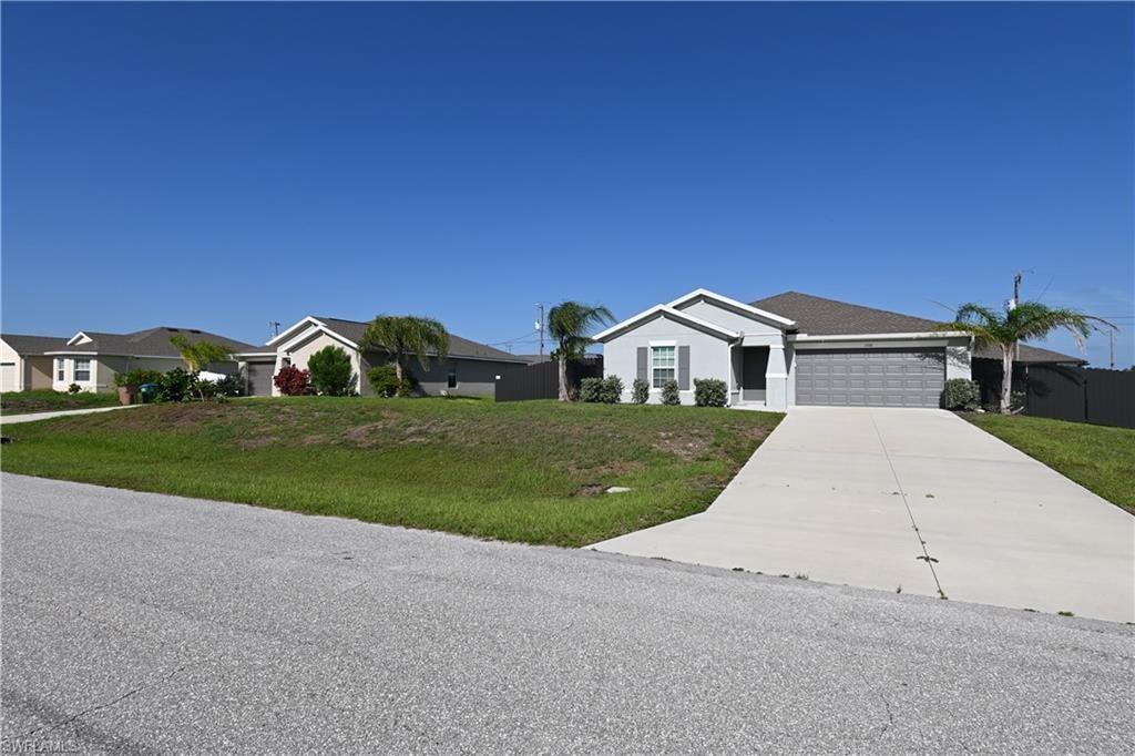 Single-story residence featuring a light gray exterior, dark gray garage door, and a concrete driveway